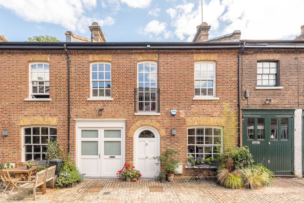 Brick house with courtyard in front and dark green garage door