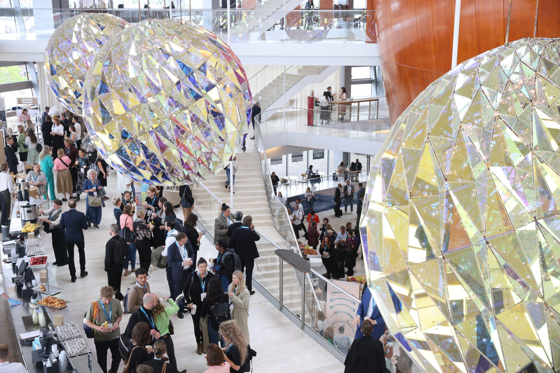 Crowds of people in spacious hall with giant mirrored ball lights overhead