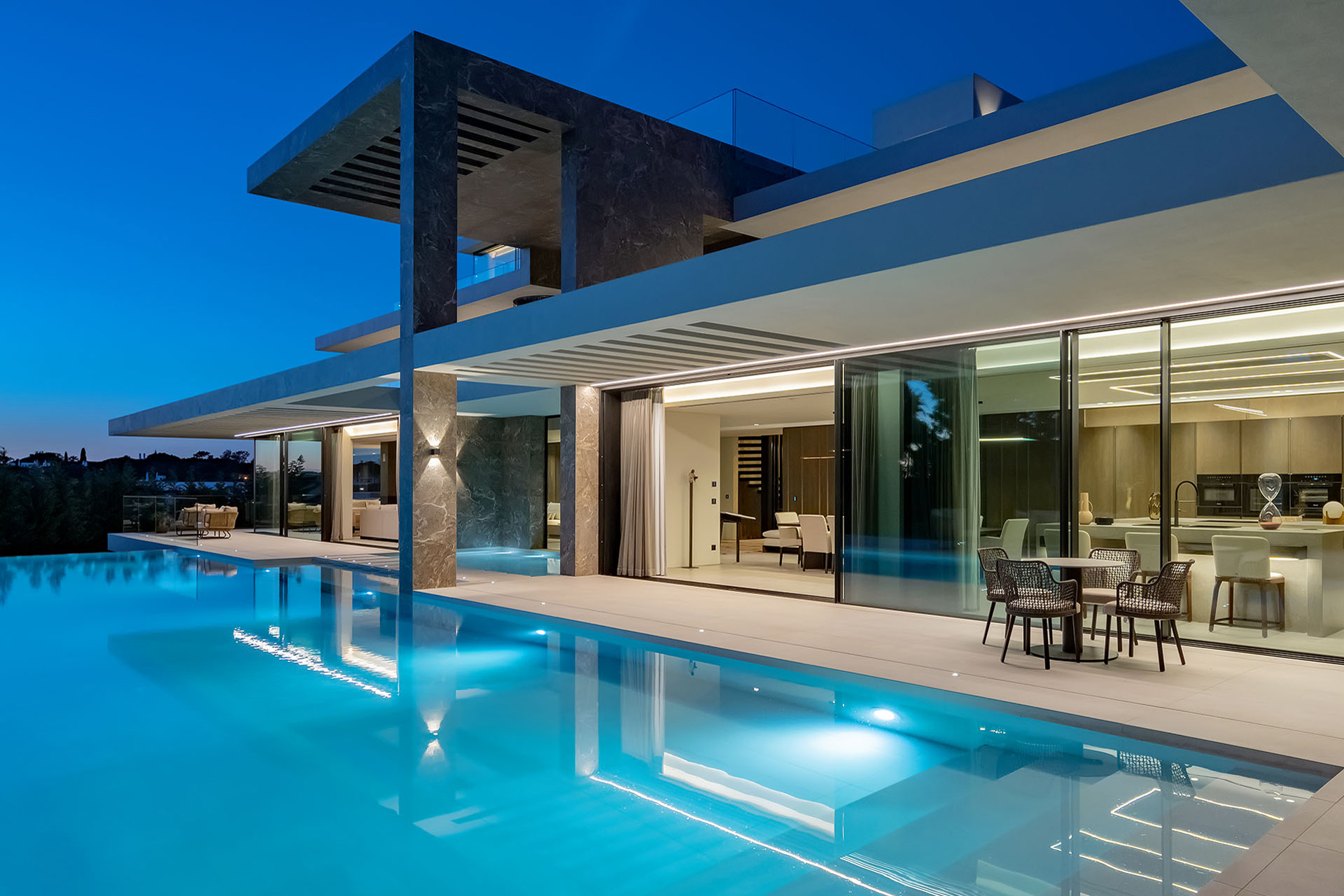 Large villa with infinity pool in front of modern kitchen with sliding doors.