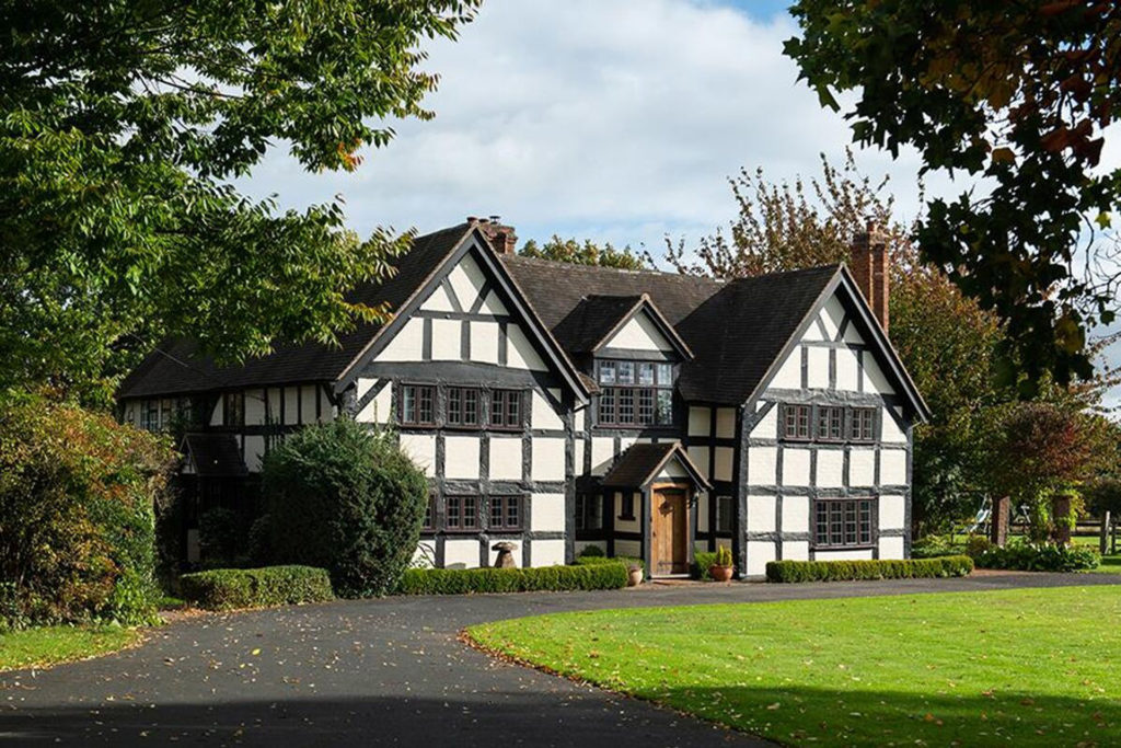 Timber framed country manor with lawns and driveway in front