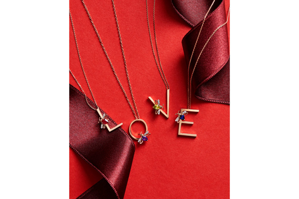 Initial necklaces spelling out 'Love' on a red background with red ribbon.
