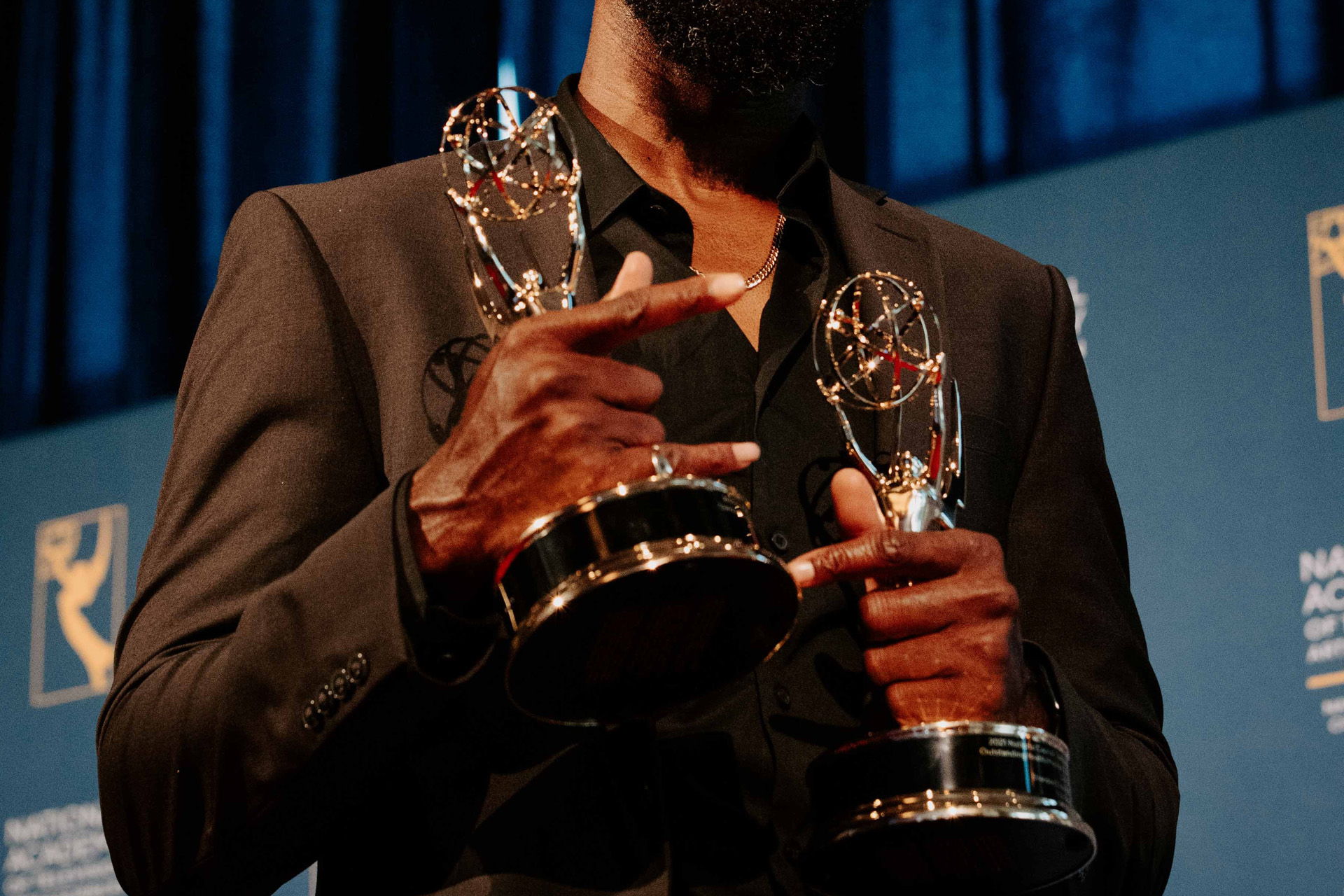 A man holding two Emmy awards