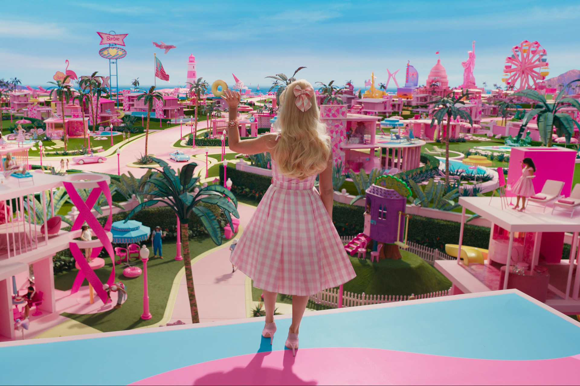 Woman in pink dress waving at pink city