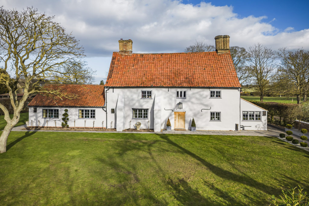 Exterior of Lordship Cottage, Swaffham Bulbeck, with grassland in the foreground.
