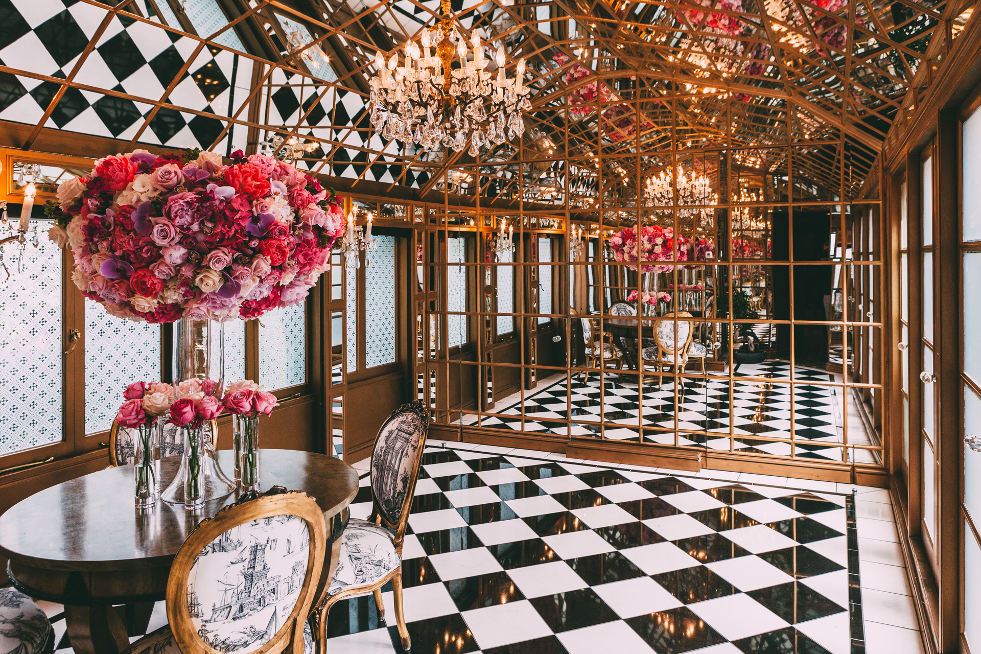 Room with black and white diamond tiles, gold ceiling, and a mirrored back wall.