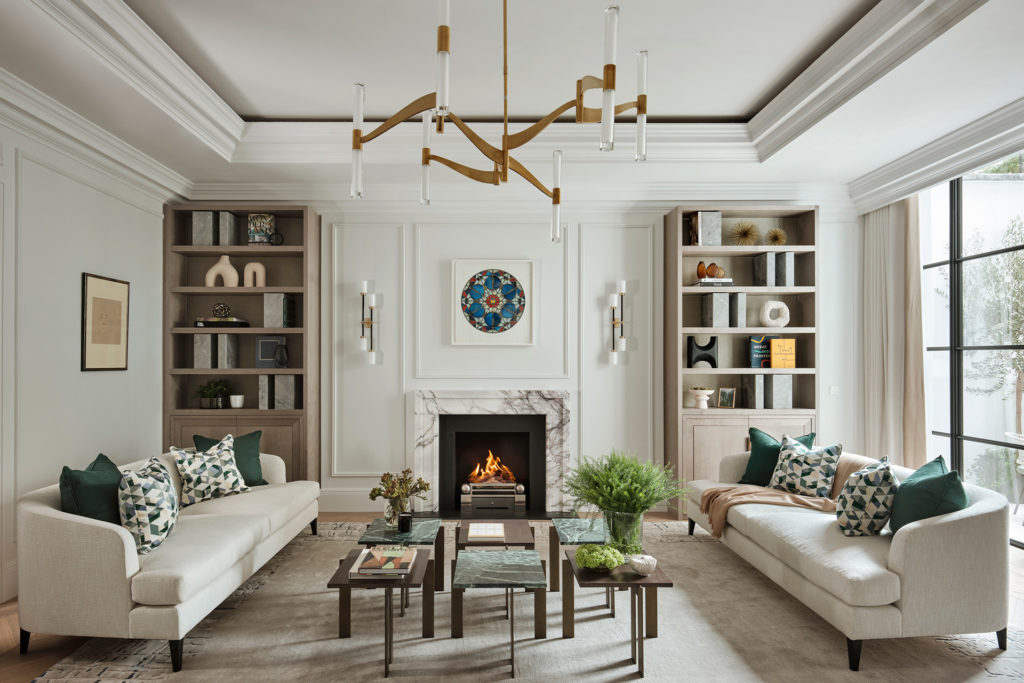 Large living room with wall panelling, white sofas, and a modern brushed gold chandelier.