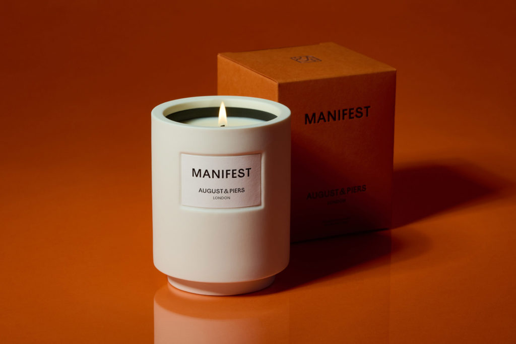 White candle next to orange box on orange background
