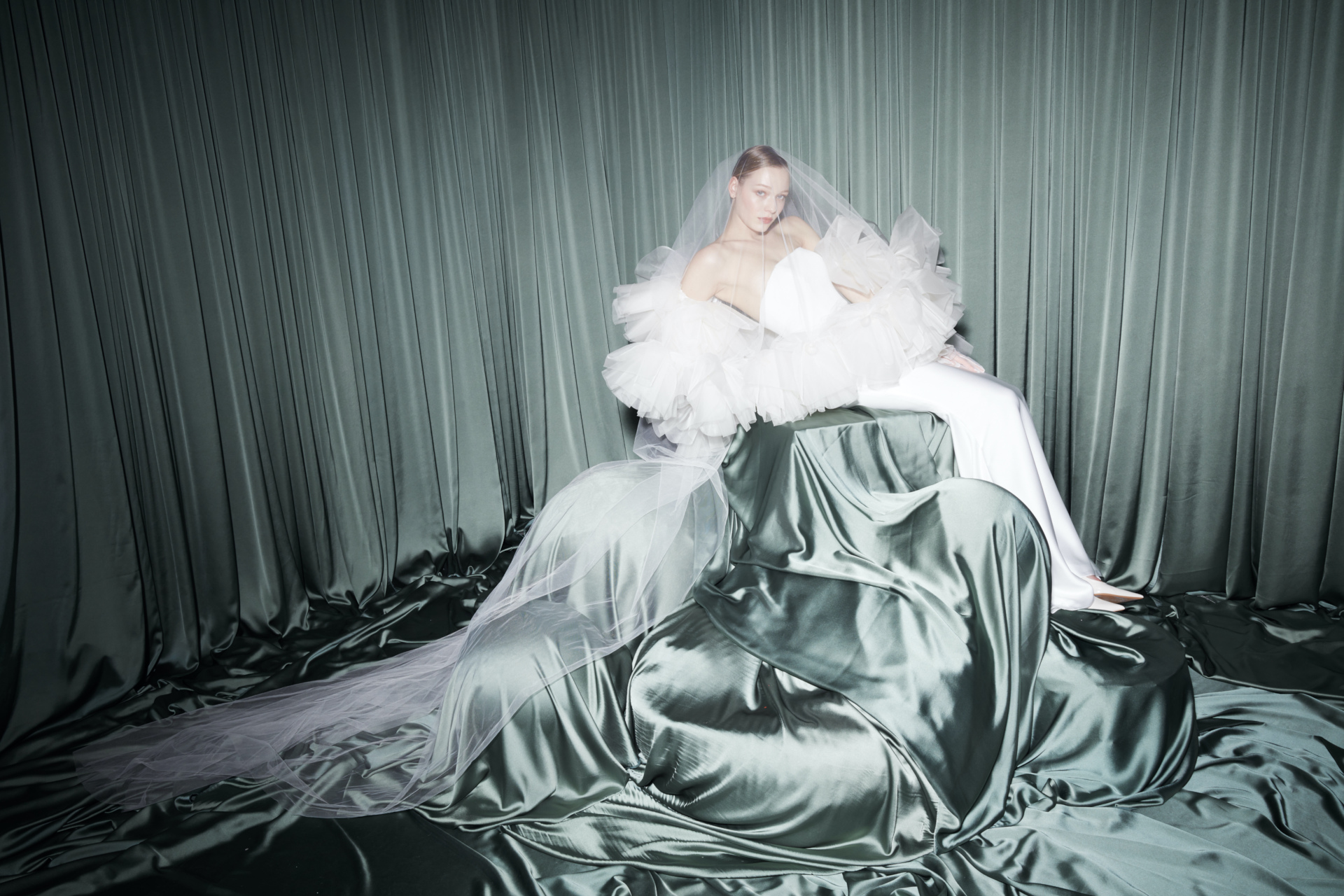 Woman sat on blue silk shape wearing wedding dress and veil