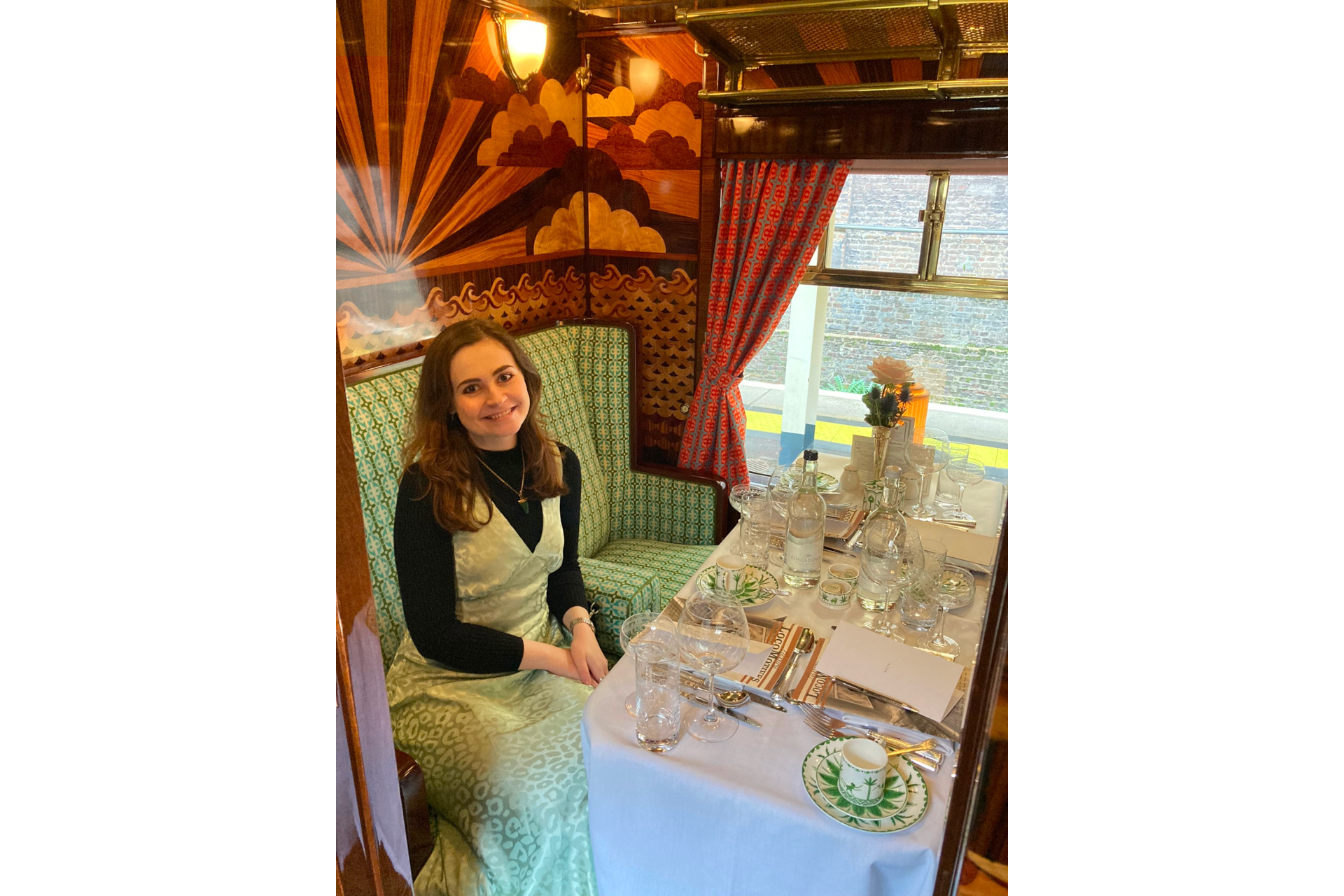 Woman in green dress in ornately decorated train cabin