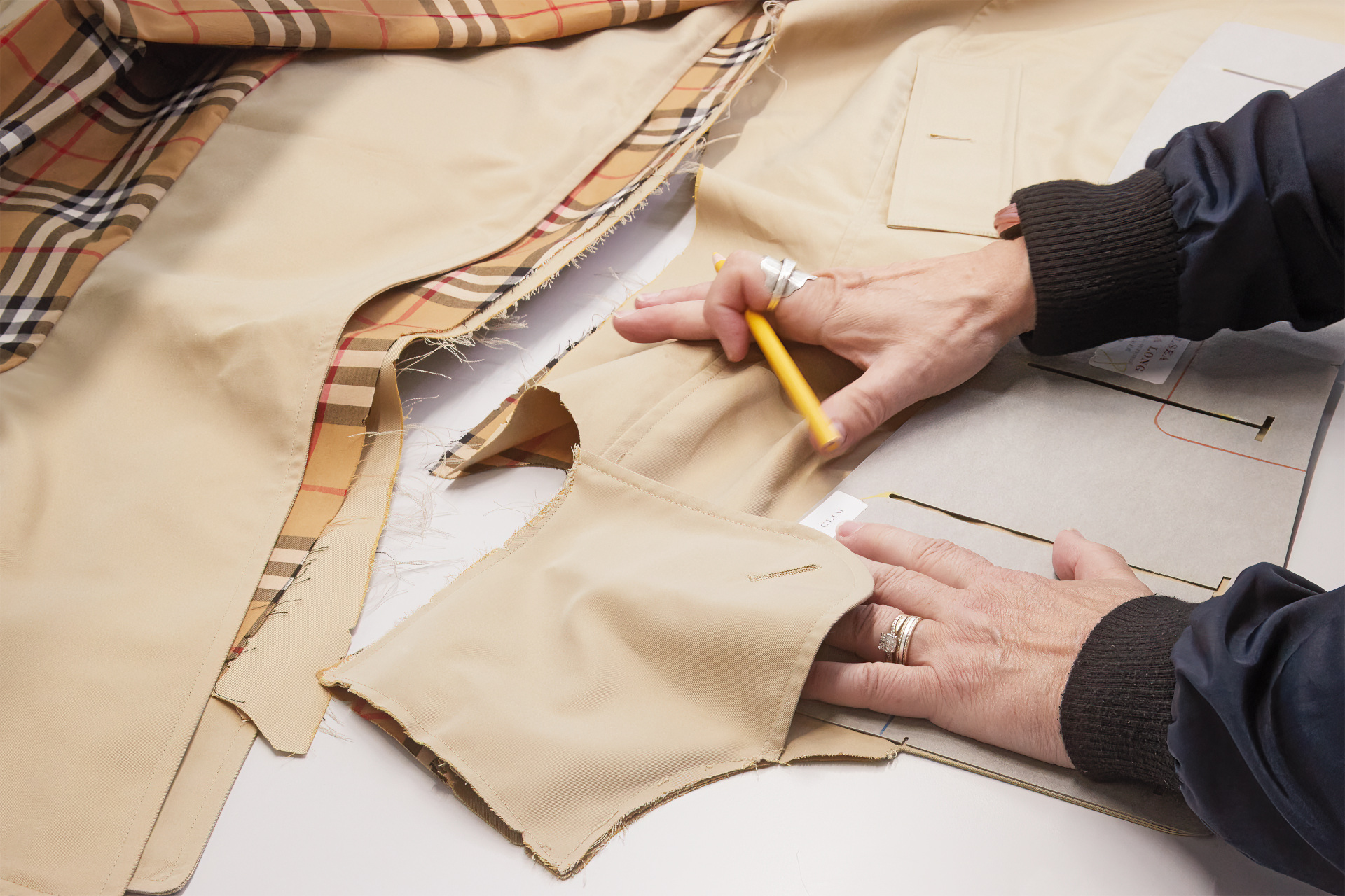 Hands cutting a Burberry trench coat