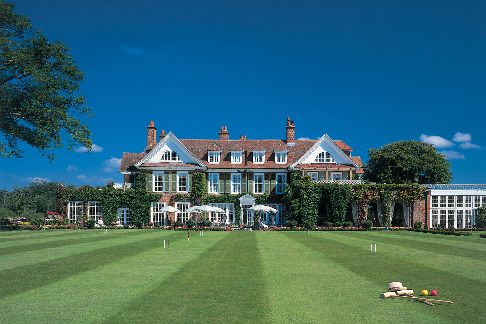 Exterior of grand red brick hotel with manicured lawns and croquet set in the foreground