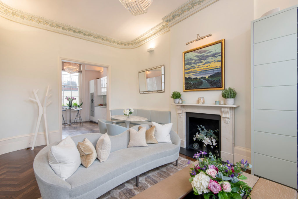 Half-moon shaped sofa with marble fireplace and landscape painting above.