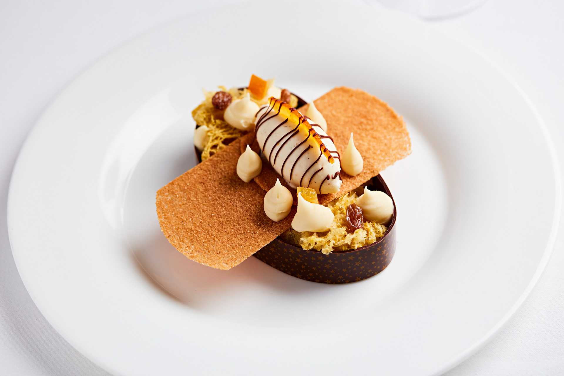 Egg-shaped sponge cake encased in chocolate with almond ice cream, a wafer biscuit, and a chocolate drizzle.