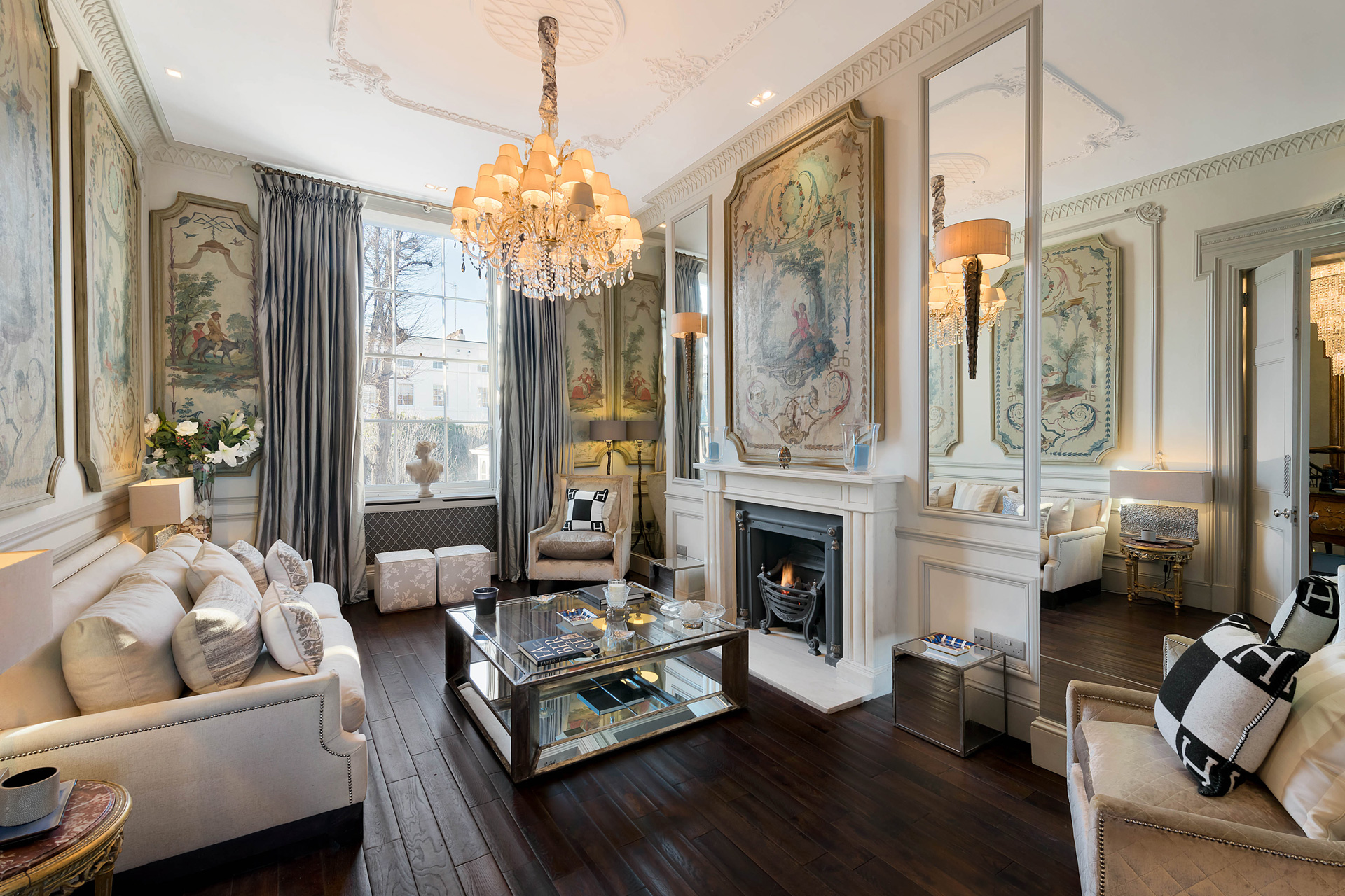 Large reception room with dark wood flooring, cream sofas, and a chandelier
