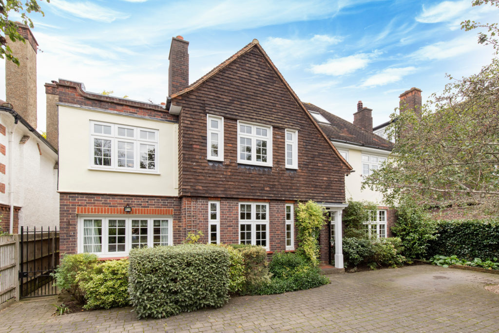 Exterior of home in Putney with large brick driveway and shrubbery in front.