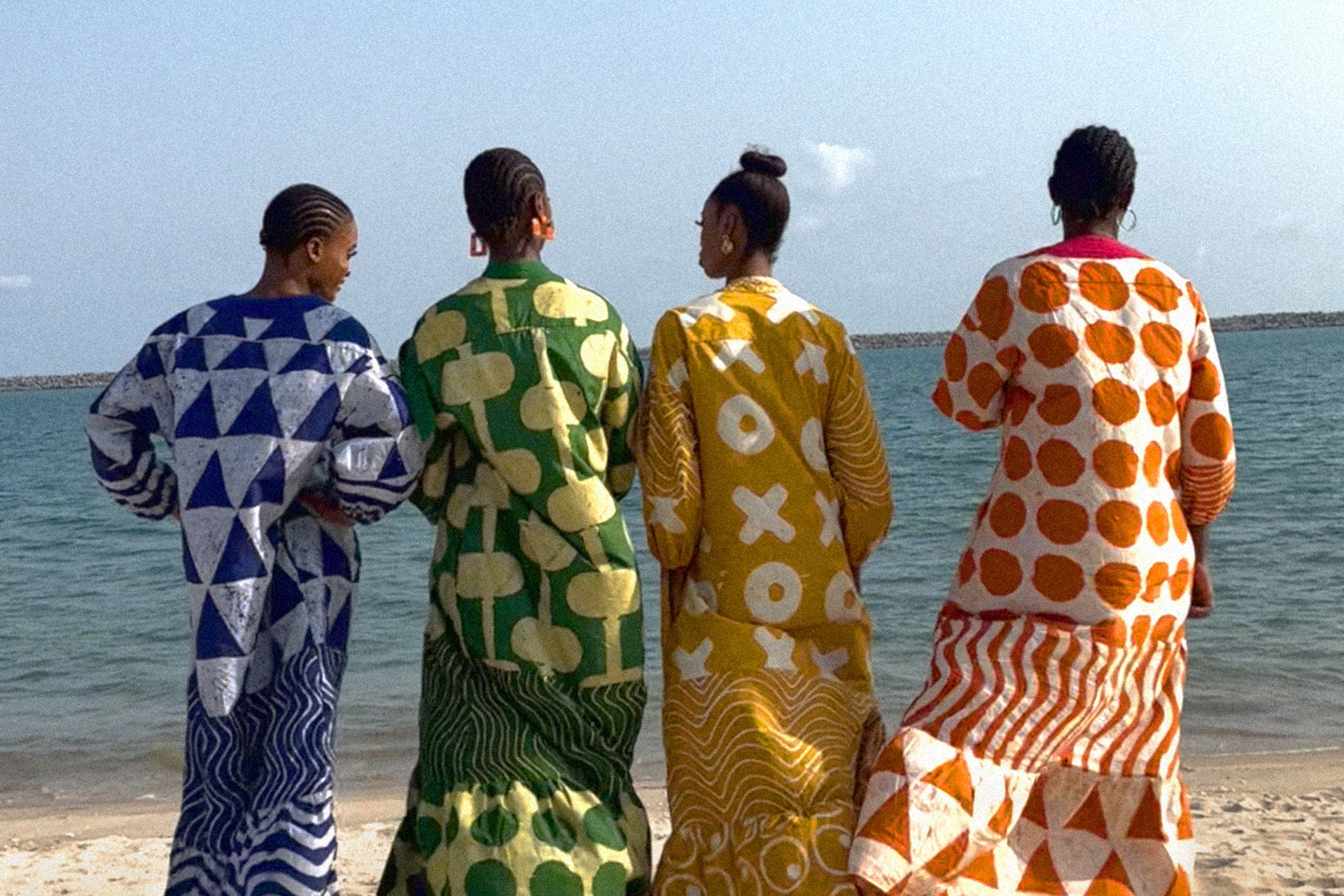 Four women on the beach in colourful print dresses