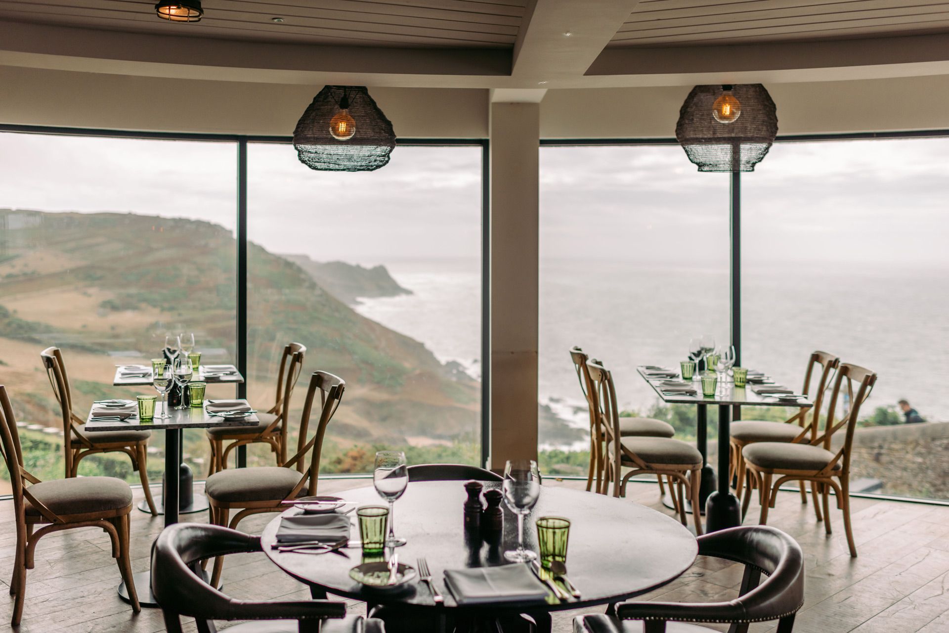 Restaurant with dark wooden chairs and floor to ceiling windows overlooking the South Devon coastline