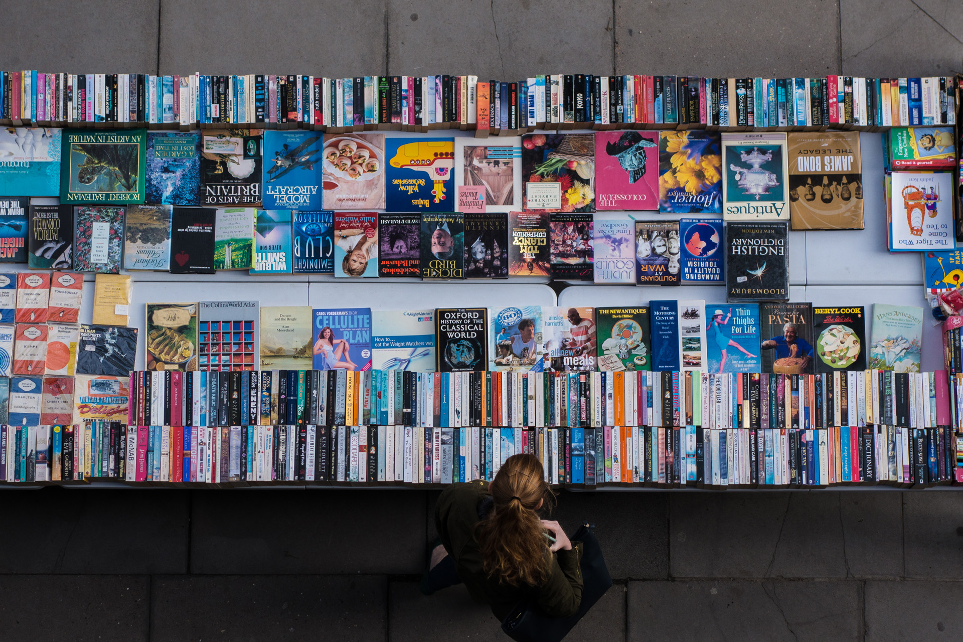 A woman exploring used and secondhand books and record bargains on London Thames Southbank.