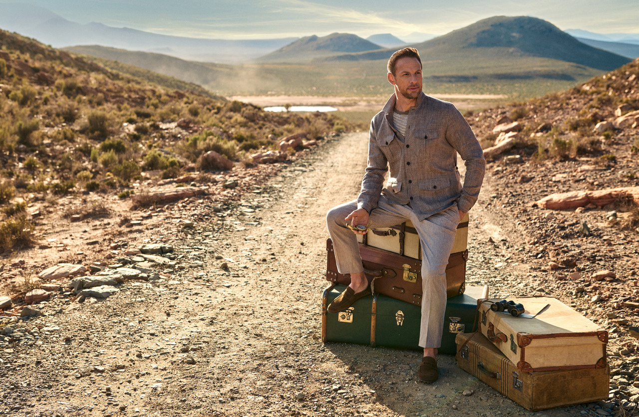 HACKETT X JENSON BUTTON SS23 sitting on suitcases in desert