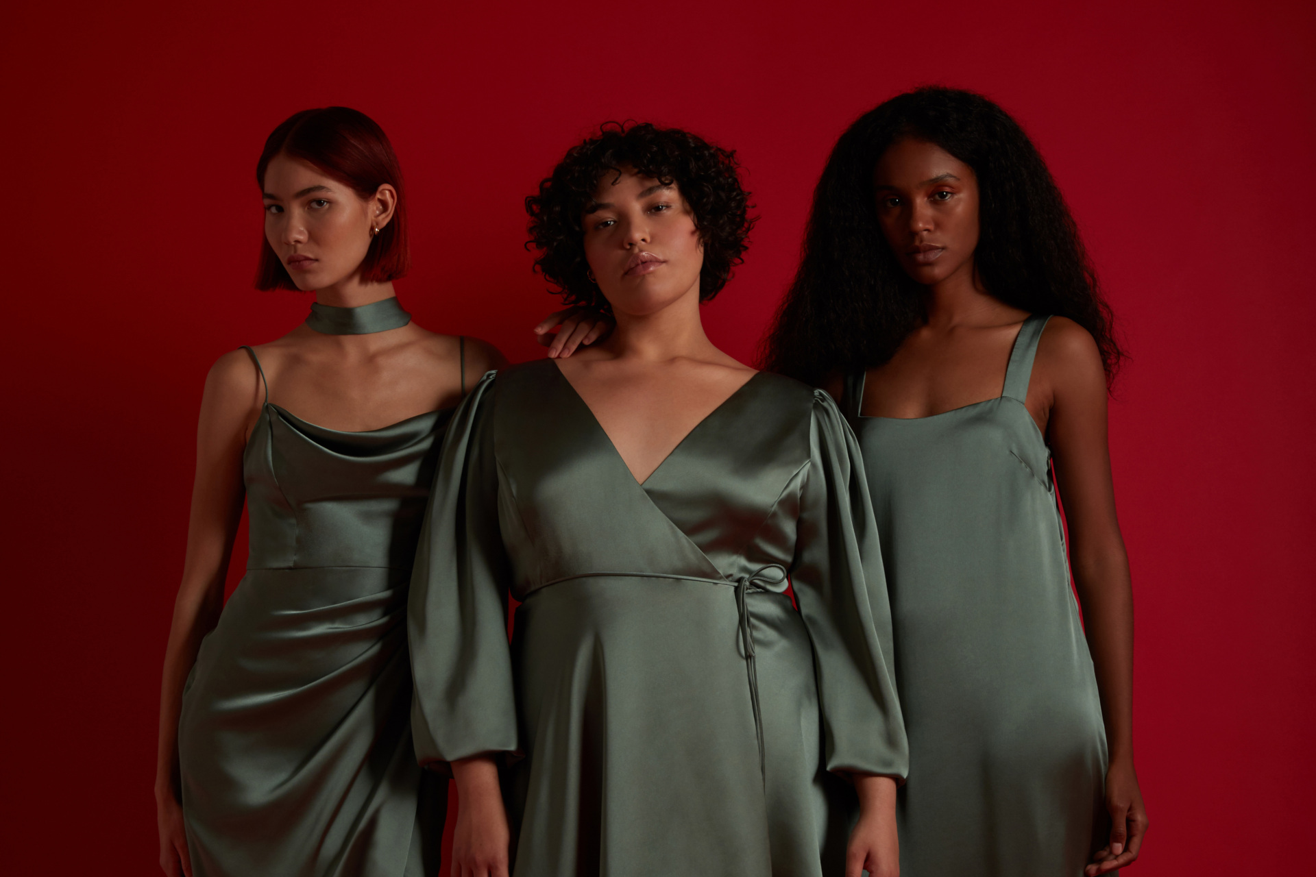 Three women in green bridesmaid dress on red background