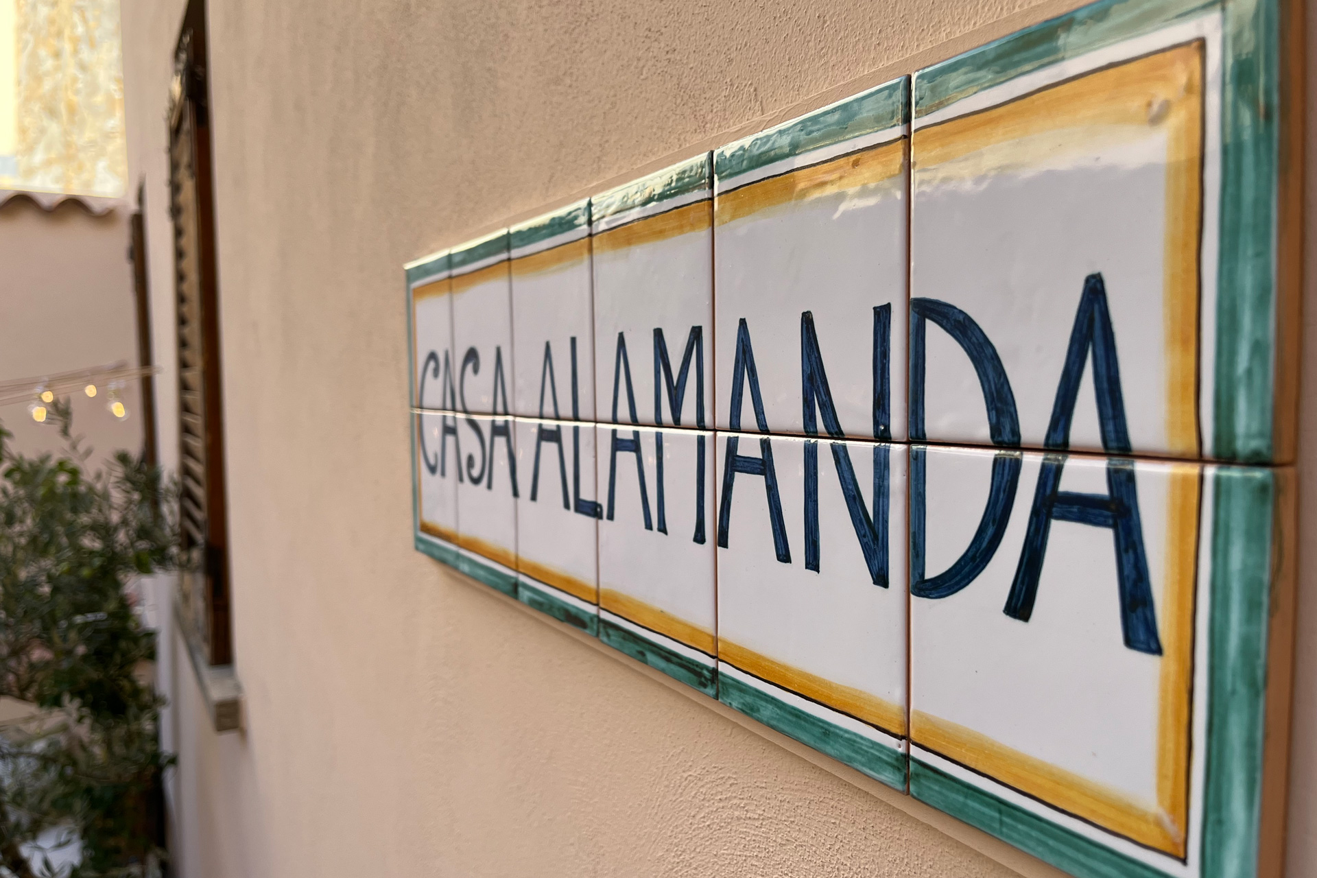 White sign with blue painted letters spelling 'Casa Alamanda'
