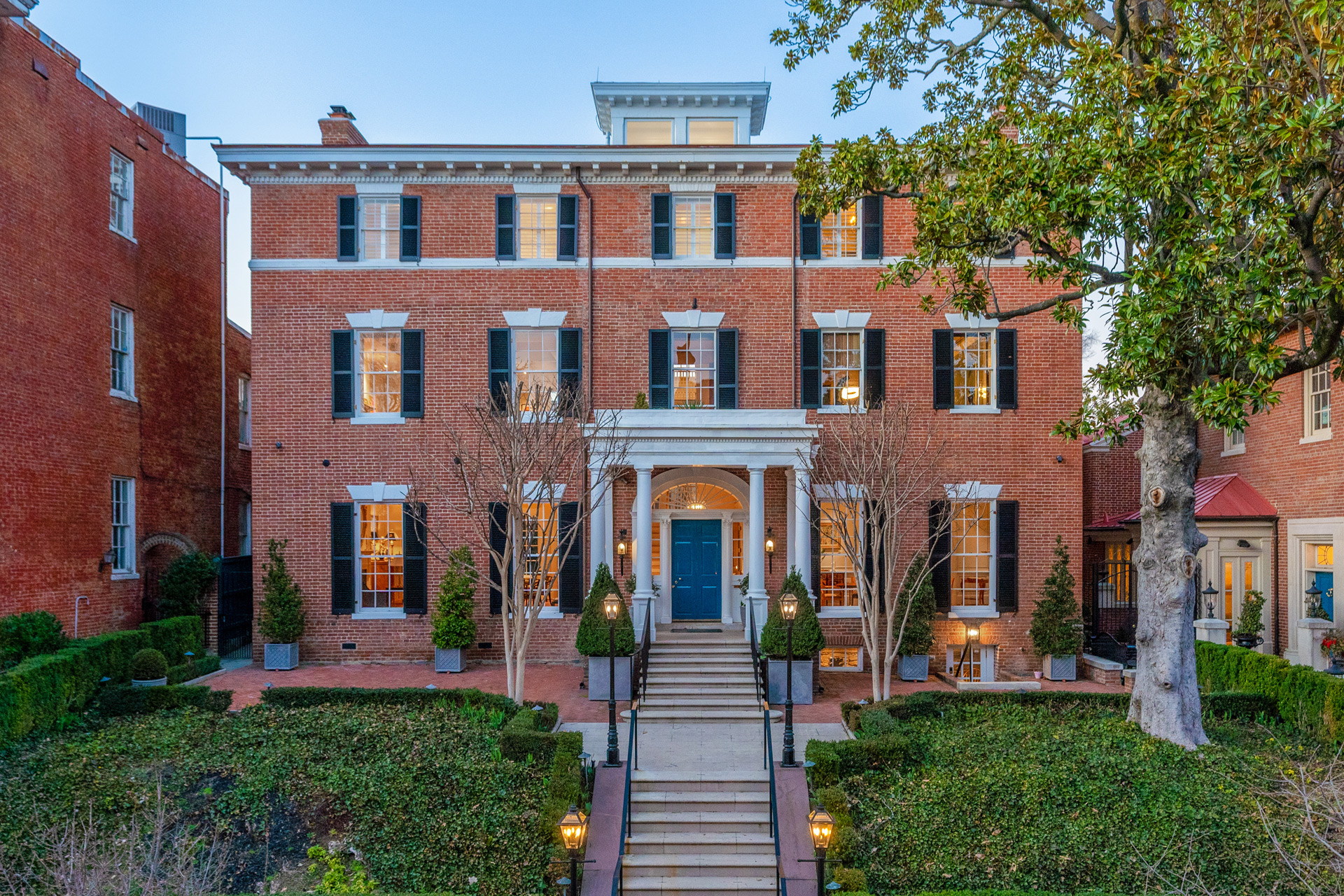 Exterior of Jackie Kennedy's former home, with red brick, white windows and wooden shutters