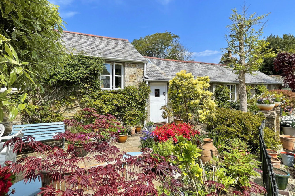 Barn conversion with flowers and foliage covering the exterior.