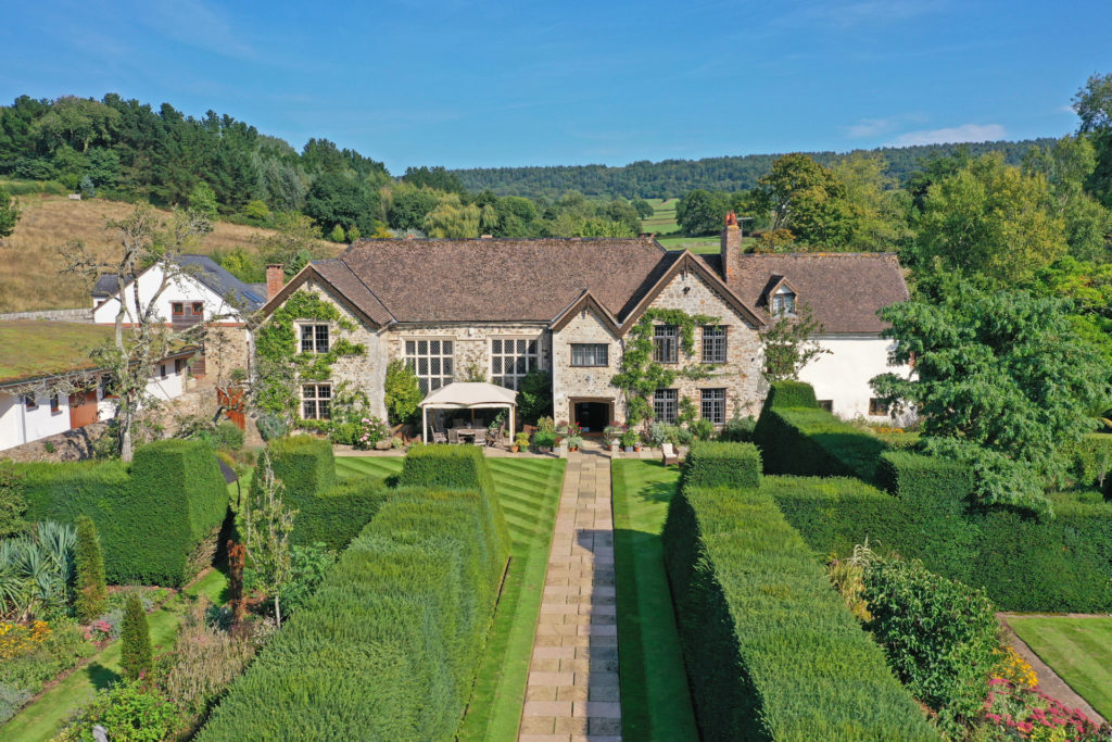 Country with box hedges, manicured lawns and a stone fountain.