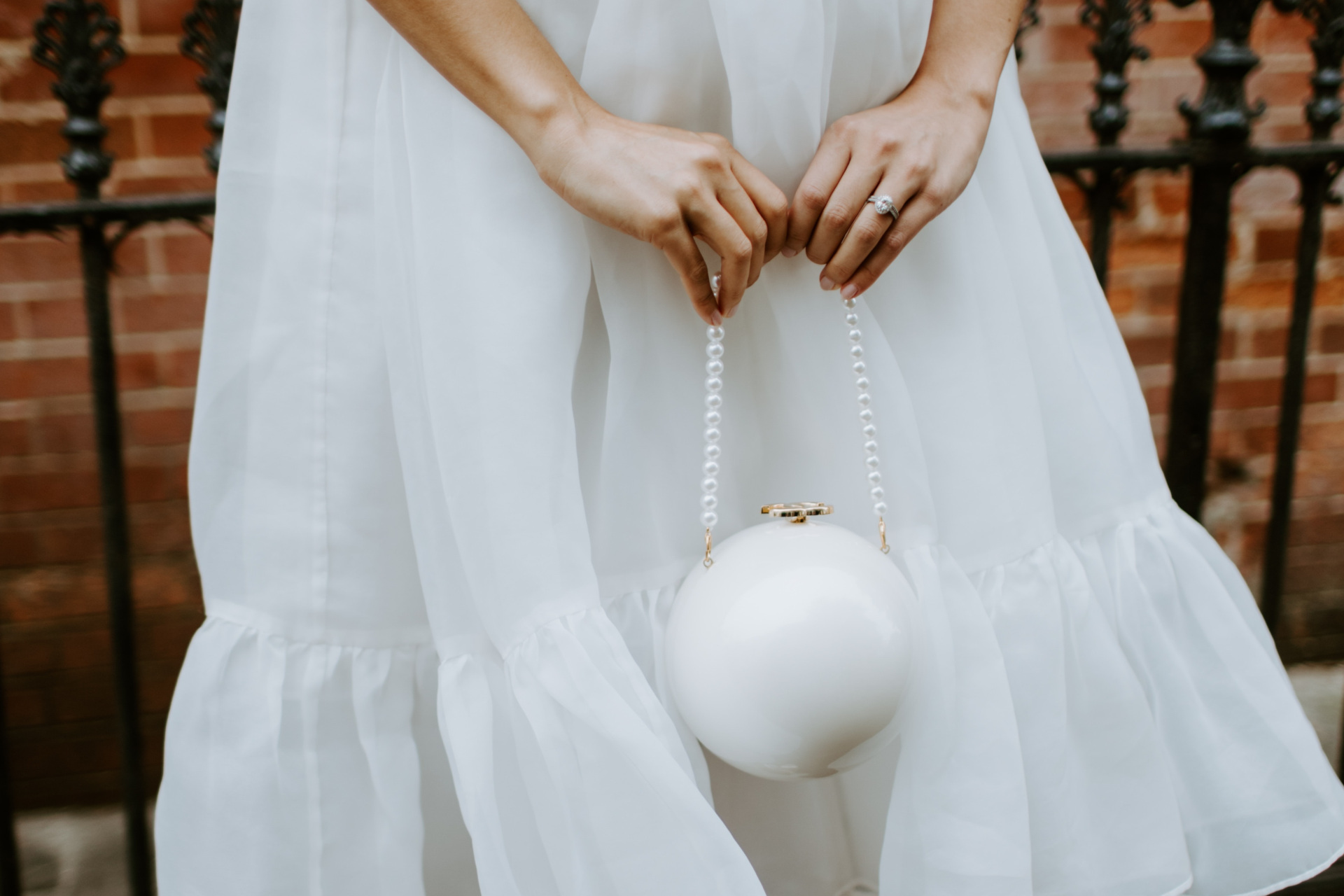 Close up of woman in white dress holding bag