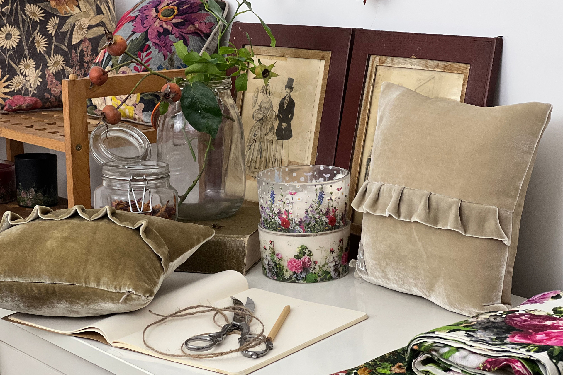 Desk cluttered with notebooks, fabrics, prints and flowers