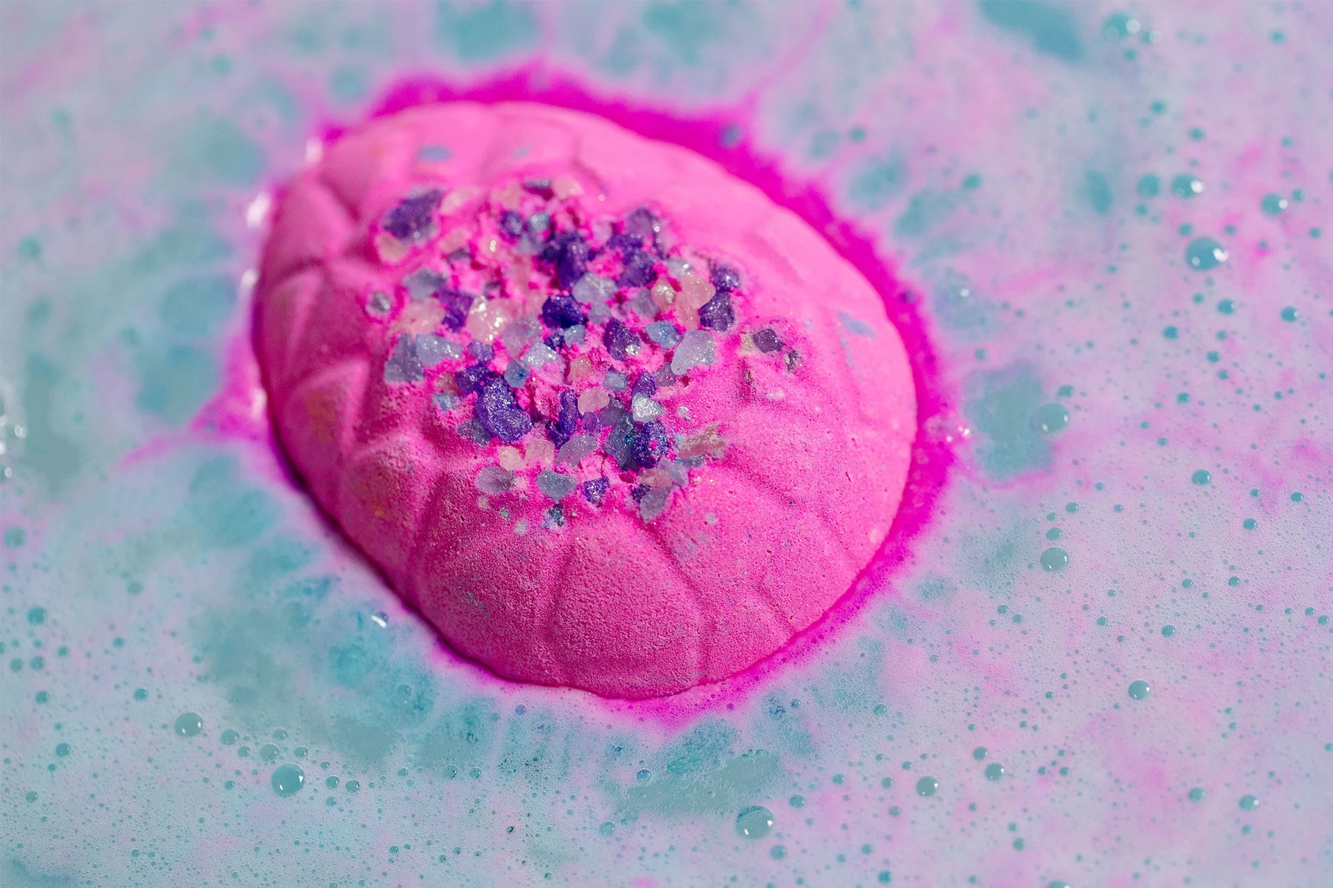 Pink egg bath bomb dissolving in water