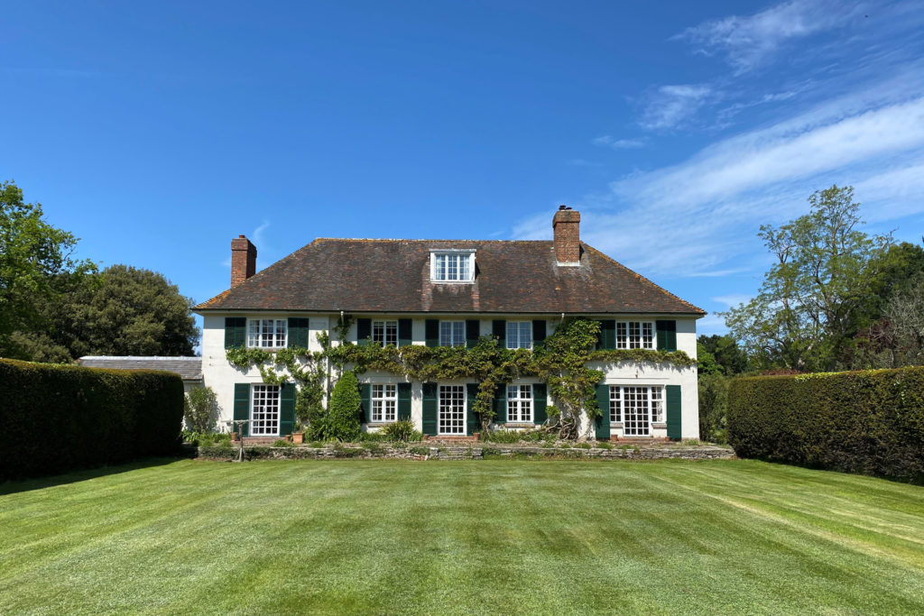 Ivy-clad country estate with white exterior and dark wooden windows.