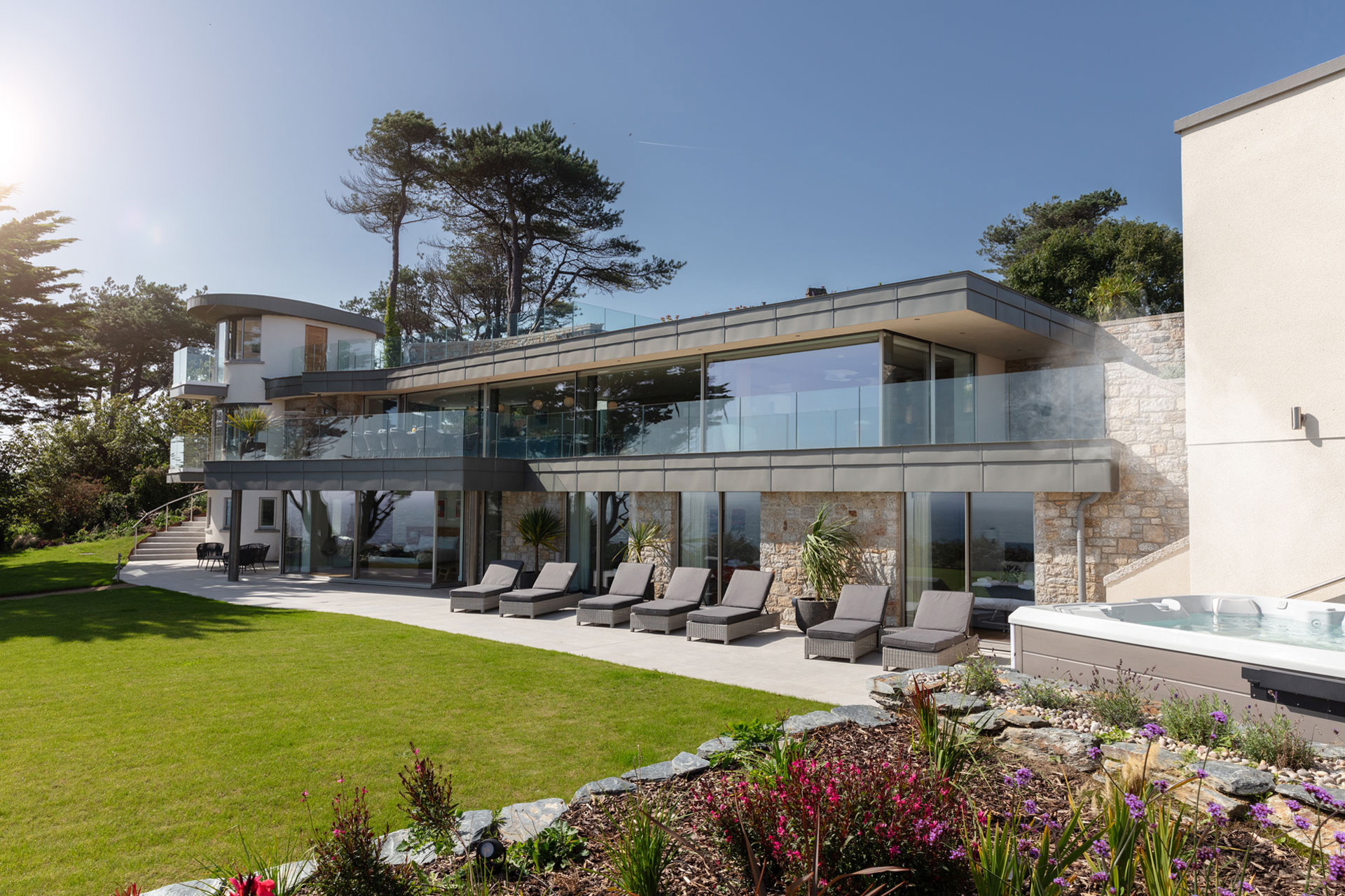 Modern coastal home with floor-to-ceiling windows and glass balconies.