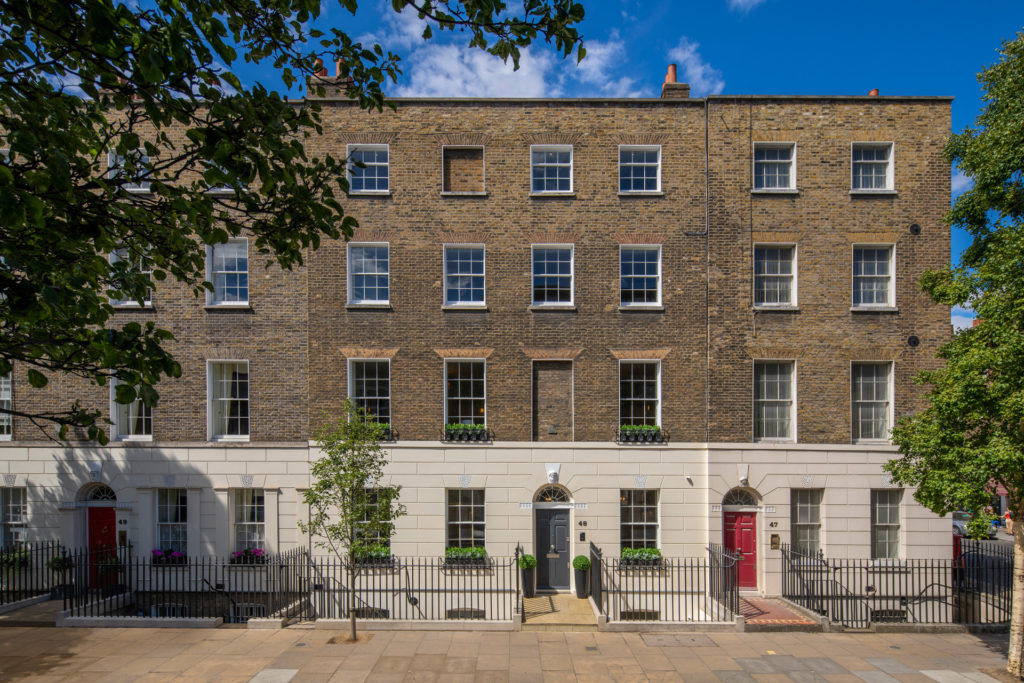 London brick townhouses with painted doors and trees lining the street,