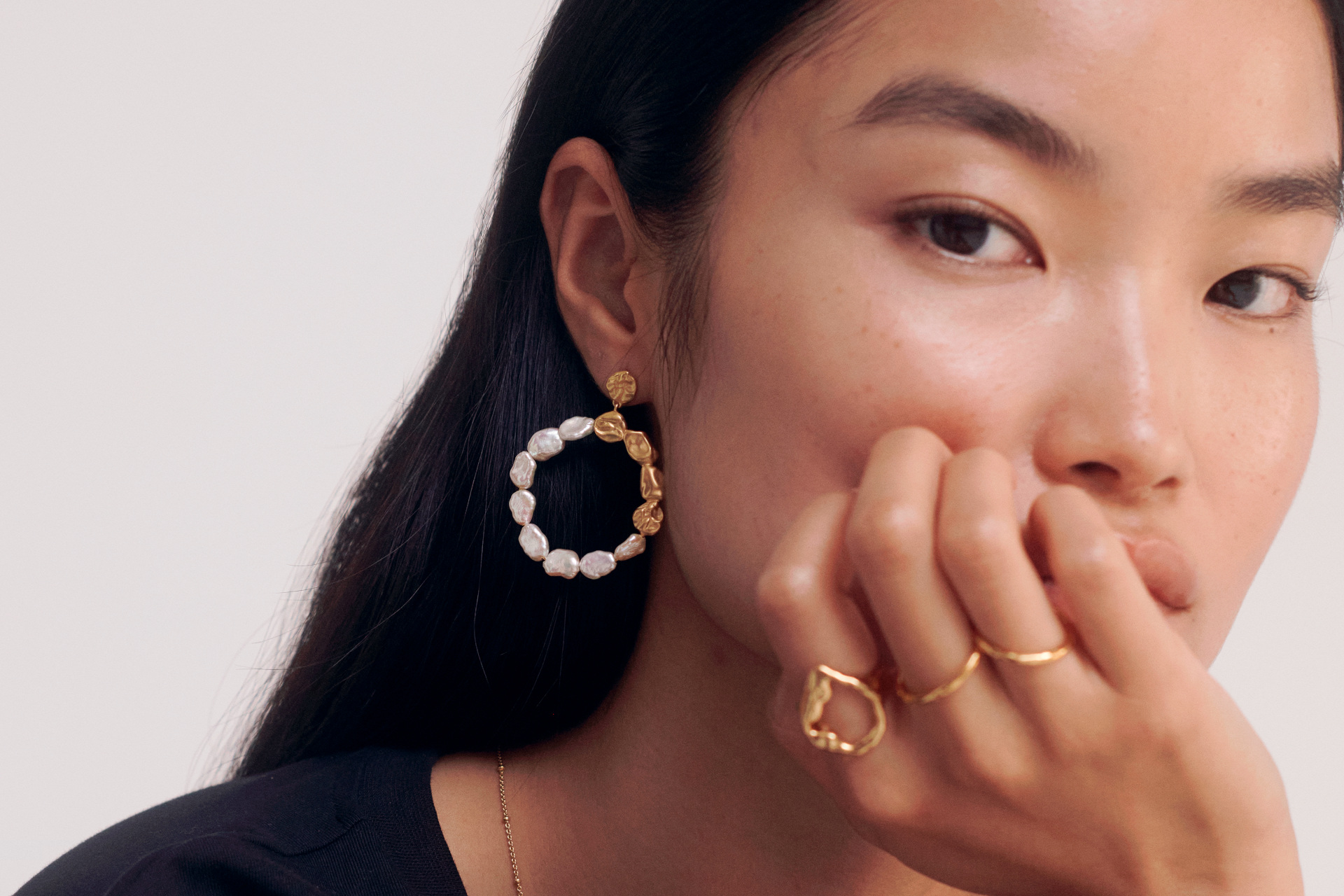 Close up of woman wearing gold and pearl jewellery