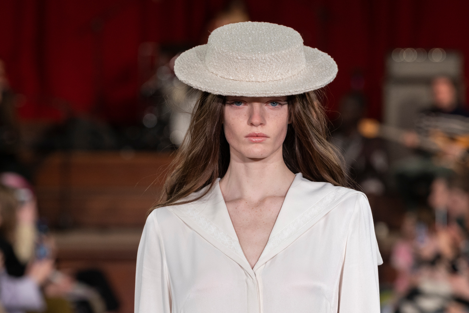 Woman in white dress and hat walking the runway