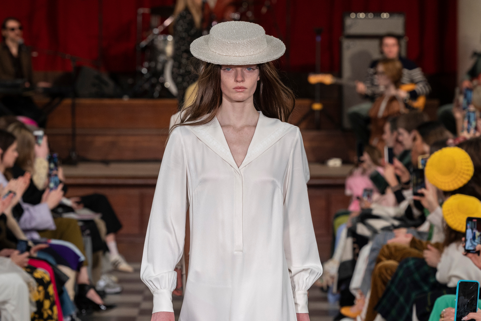 Woman in white dress and hat walking the runway