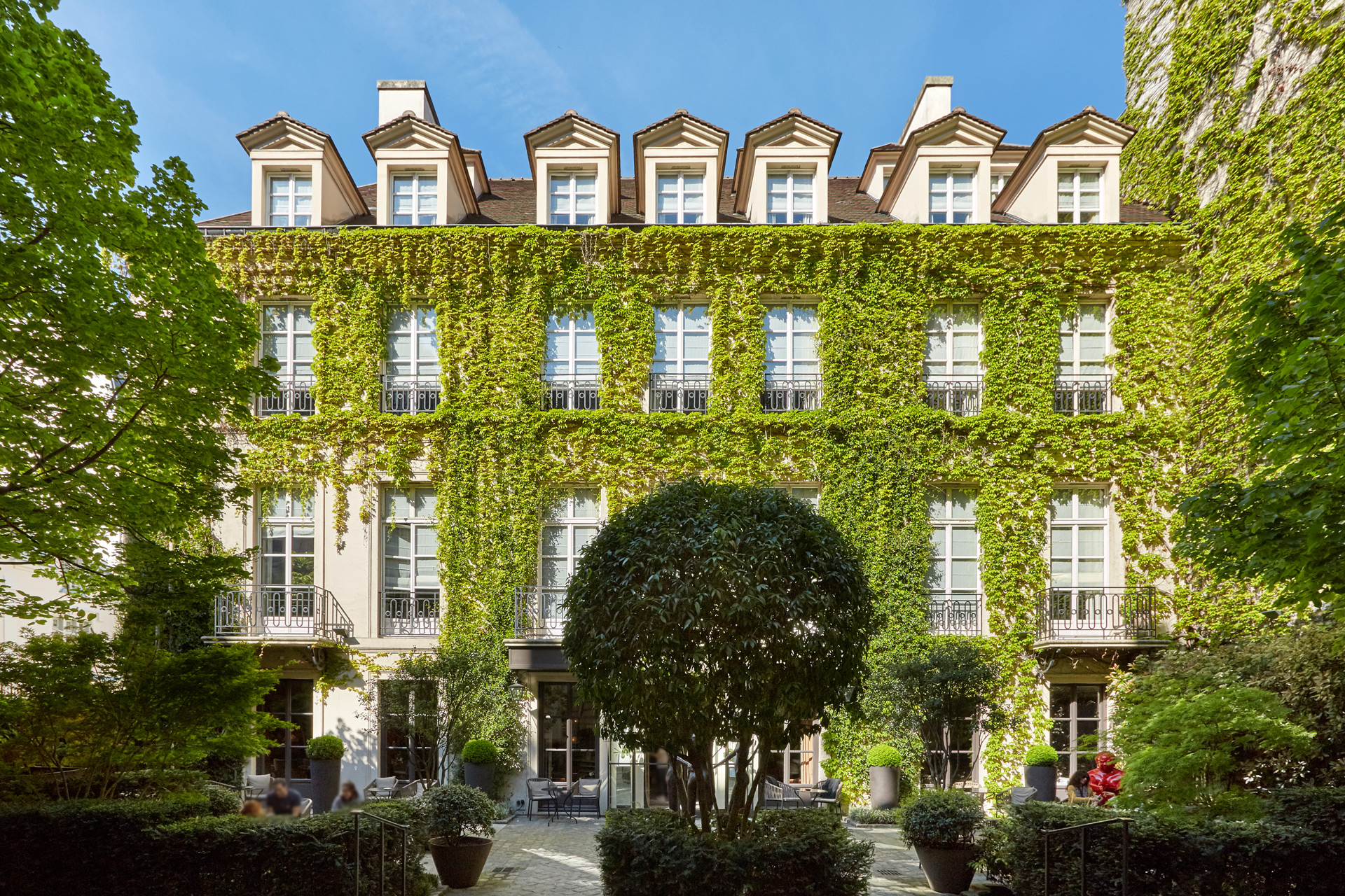 Hotel exterior with ivy-clad walls and a large landscaped hedge in the centre of the front courtyard