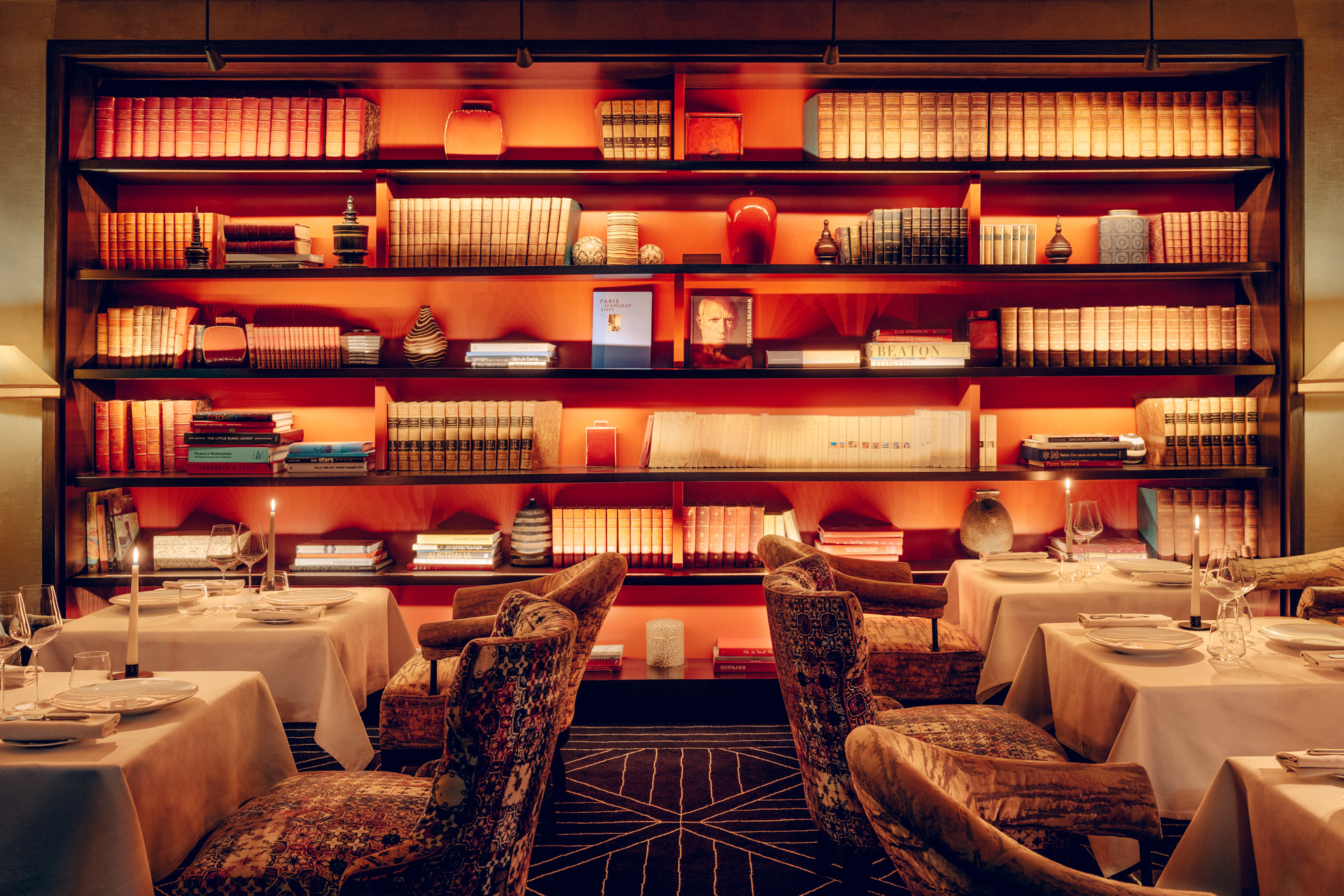 Restaurant in Pavillion de la Reine with orange accents, low lighting and velvet patterned chairs