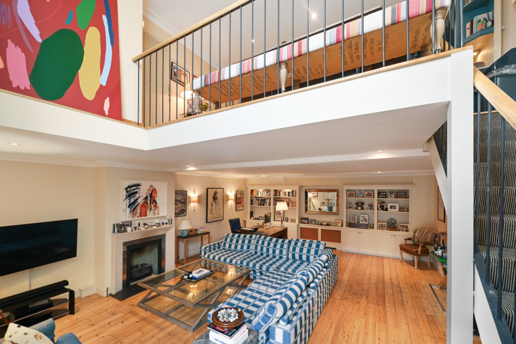 Mezzanine apartment with living room with blue striped sofa and kitchen/dining room above