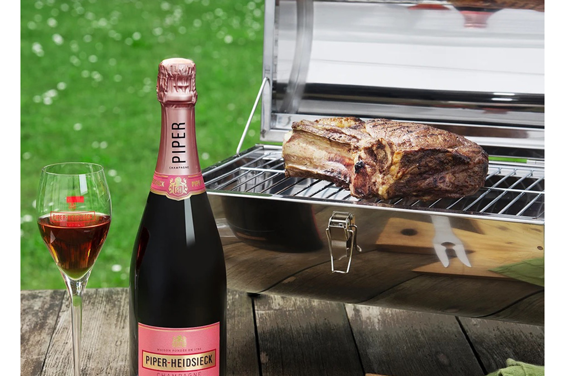 Silver camping BBQ with bottle of Piper champagne beside it