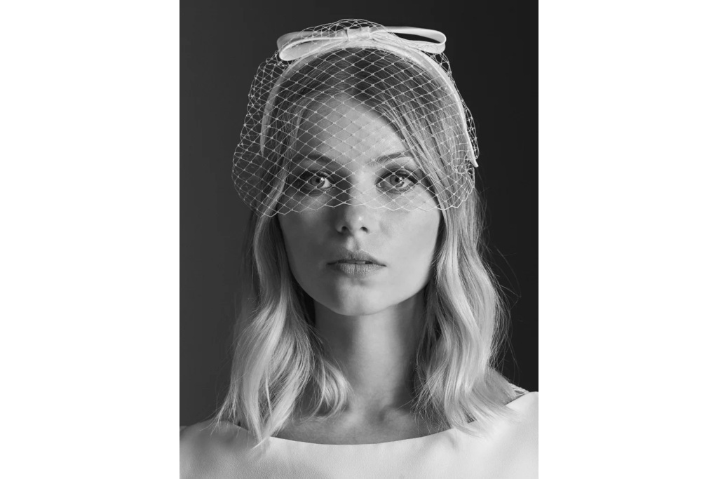Black and white image of woman wearing white headband with net veil