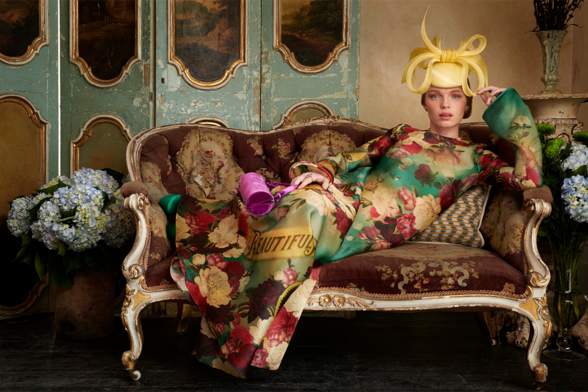 Woman in colourful dress and hart lounging on ornate sofa