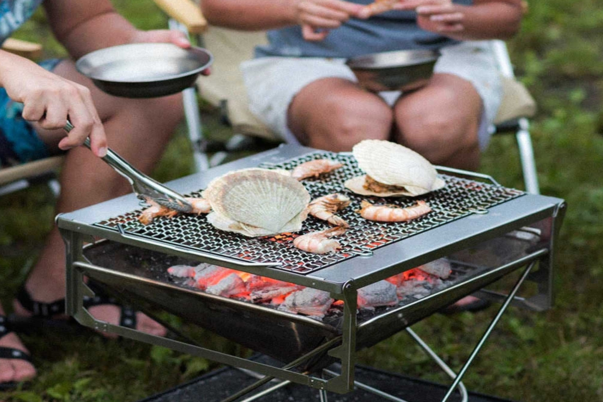 Silver grill with clams and prawns cooking on top