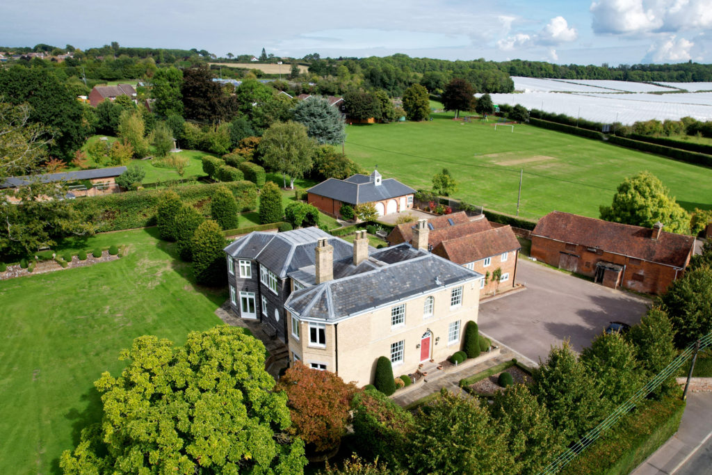 Aerial view of large home in Kent with a brick building and glass extension plus field surrounding