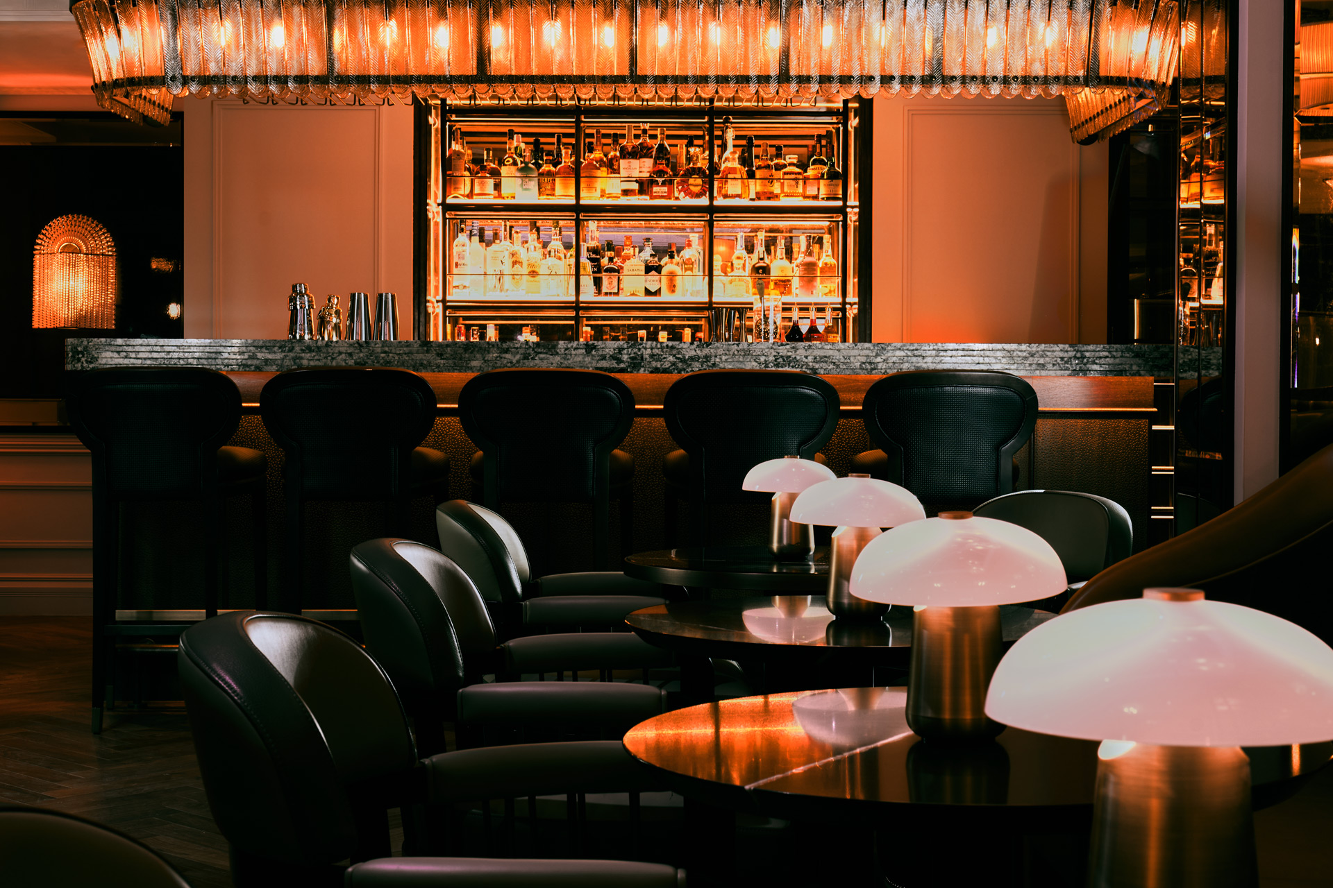 Restaurant interior with black velvet seating, white lamps and bar