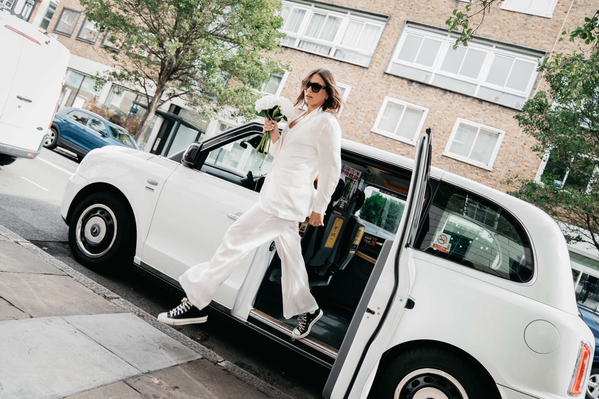Woman in white suit getting out of white car