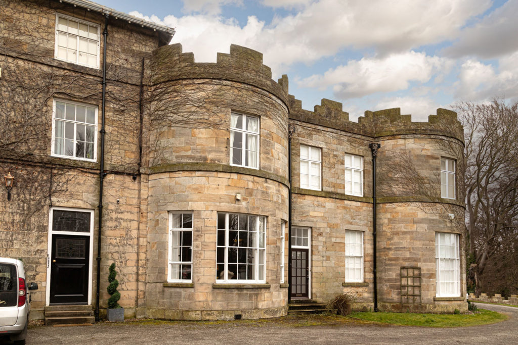Castellated house with turrets and arched walls.