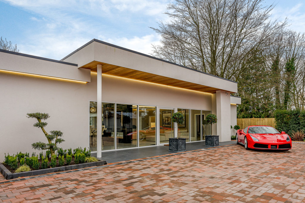 Modern home with floor-to-ceiling windows and a sports car outside