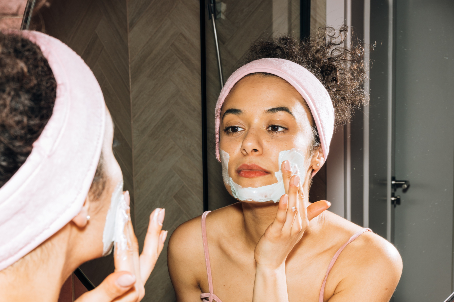 Woman applying cream to her face in the mirror